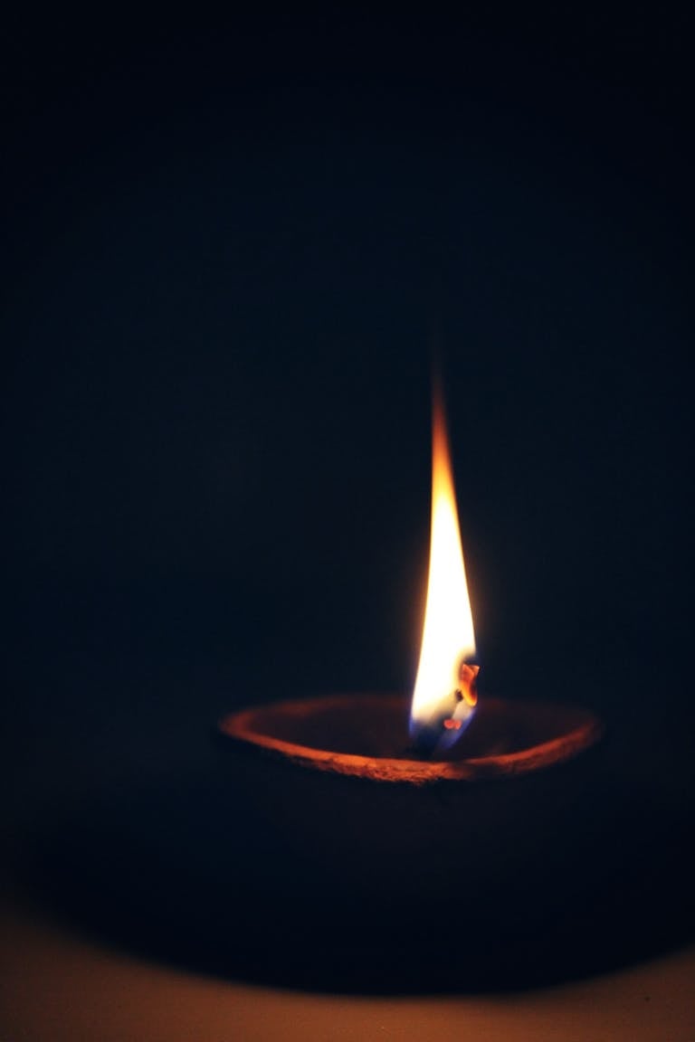 A close-up capture of a candle's flame illuminating the dark ambiance, creating a peaceful mood.